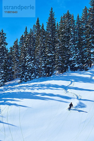 Fernansicht eines Mannes beim Skifahren in schneebedeckter Landschaft  Aspen  Colorado  USA