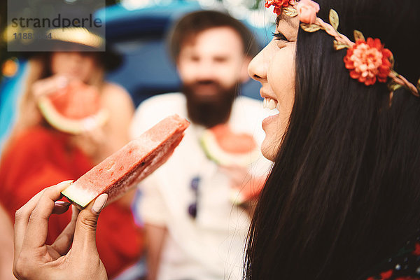 Junge Boho-Frau isst Melonenscheibe beim Festival