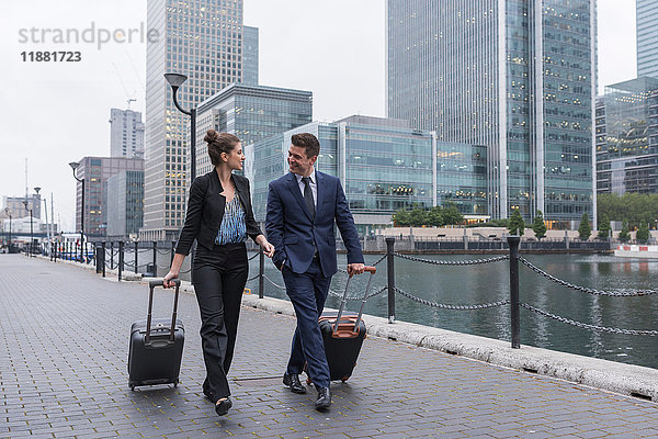 Geschäftsmann und Geschäftsfrau  die Gepäckwagen ziehen  Canary Wharf  London  Großbritannien