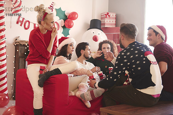 Junge Frauen und Männer essen auf der Weihnachtsfeier Popcorn auf dem Sofa