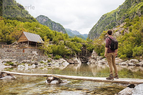 Mann auf Holzbrücke mit Blick auf Hütte  Verfluchte Berge  Theth  Shkoder  Albanien  Europa