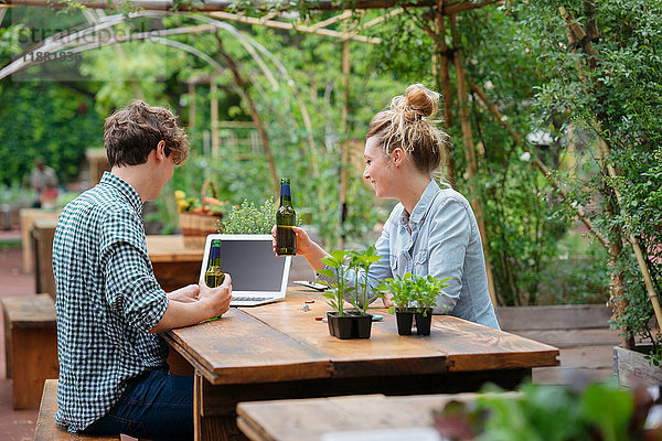 Paar mit Bier im Garten mit Laptop