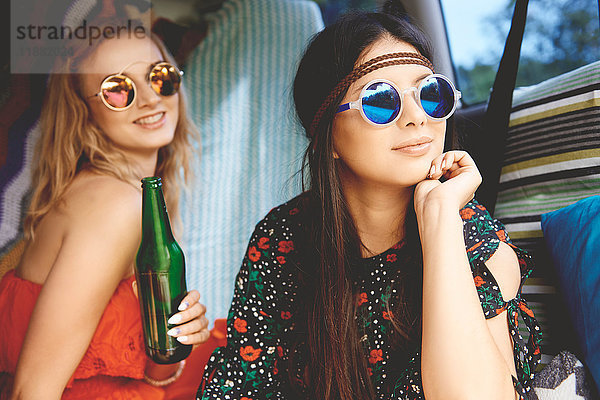 Zwei junge Boho-Frauen mit Sonnenbrille im Wohnwagen