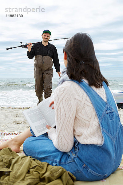 Junge Frau betrachtet Meeresfischer-Freund am Strand