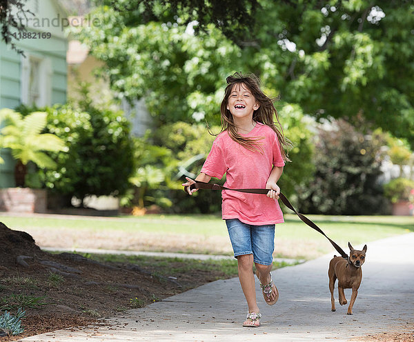 Mädchen geht mit Hund auf der Straße spazieren