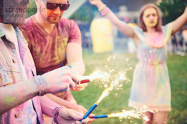 Junge Männer mit farbigem Kreidepulver bedeckt  die beim Fest Wunderkerzen halten