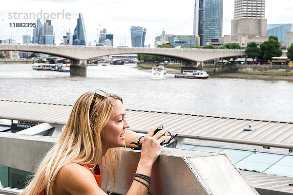 Weibliche Touristin lehnt an der Wand und fotografiert die Londoner Sicht