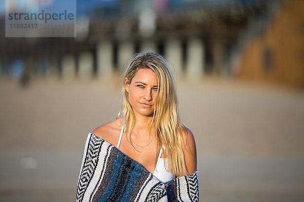 Porträt einer schwülen  in eine Decke gehüllten jungen Frau am Strand  Santa Monica  Kalifornien  USA