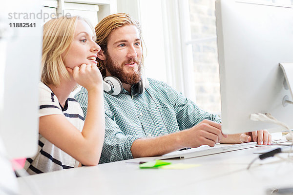 Designer und Designerinnen schauen sich Desktop-Computer im Kreativstudio an