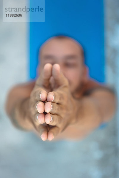 Draufsicht auf einen Yoga praktizierenden Mann  der auf einer Yogamatte steht und die Hände zusammenhält