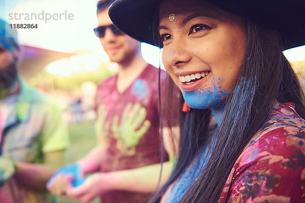Junge Boho-Frau mit blauem Kreidepulver am Kinn beim Festival