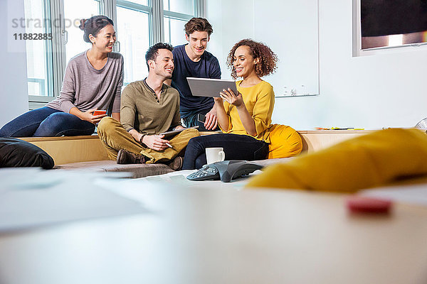 Digital-Designer auf Büro-Sofa mit Blick auf digitales Tablet