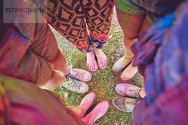 Draufsicht auf junge Erwachsene in einem mit farbigem Kreidepulver bedeckten Kreis beim Festival