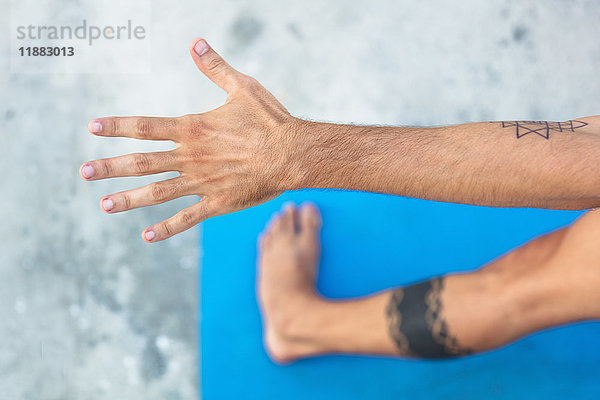 Draufsicht eines Yoga praktizierenden Mannes  stehend auf Yogamatte mit ausgestrecktem Arm
