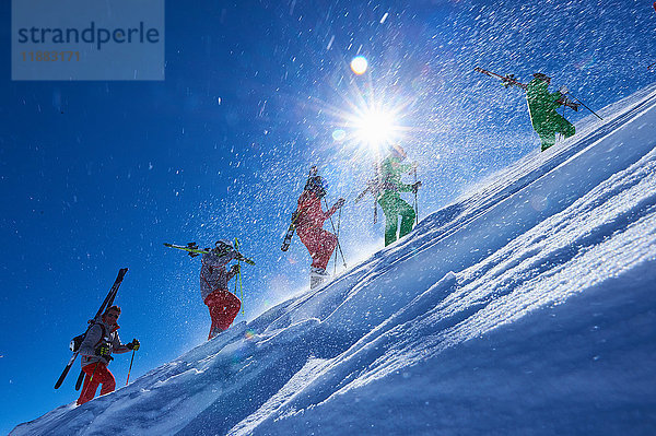 Fünf männliche Skifahrer stapfen den steilen  sonnenbeschienenen Berghang hinauf  Aspen  Colorado  USA