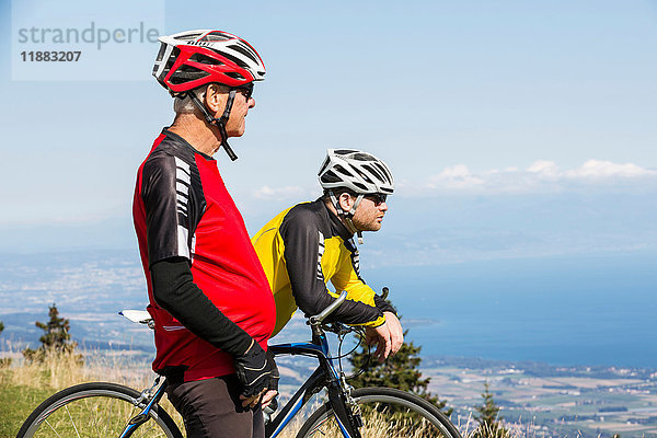 Älterer Mann und Enkel  in Fahrradkleidung  auf einem Hügel stehend  Blick auf Aussicht  Genf  Schweiz  Europa