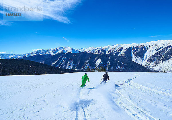 Rückansicht von zwei Männern beim Abfahren einer schneebedeckten Skipiste  Aspen  Colorado  USA