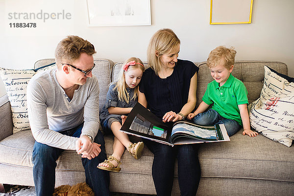 Eltern auf dem Sofa  die ihrem Sohn und ihrer Tochter ein Märchenbuch vorlesen