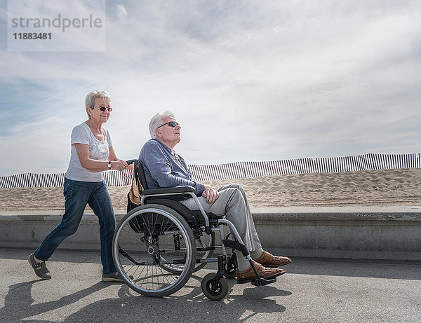 Ältere Frau schiebt Ehemann im Rollstuhl am Strand  Santa Monica  Kalifornien  USA