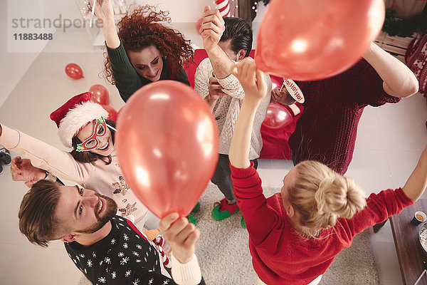 Draufsicht auf junge erwachsene Freunde  die auf der Weihnachtsfeier mit Luftballons tanzen