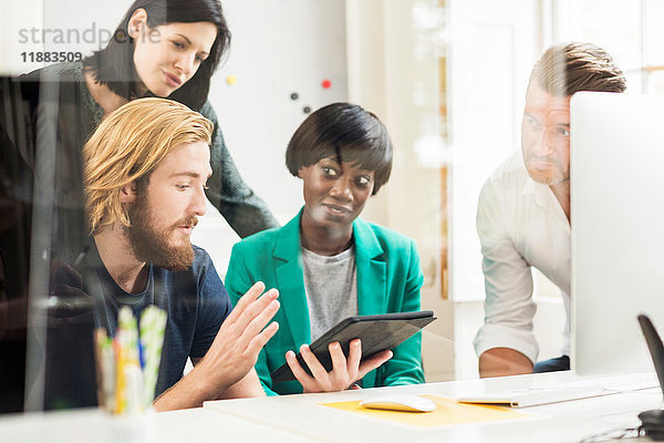 Junger männlicher Designer erklärt Idee bei Teambesprechung im Kreativstudio