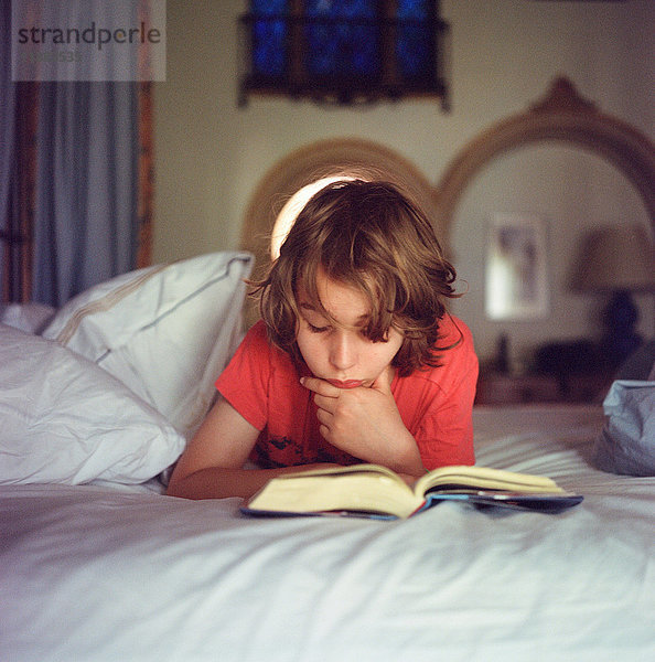 Junge entspannt sich im Bett  liest Buch