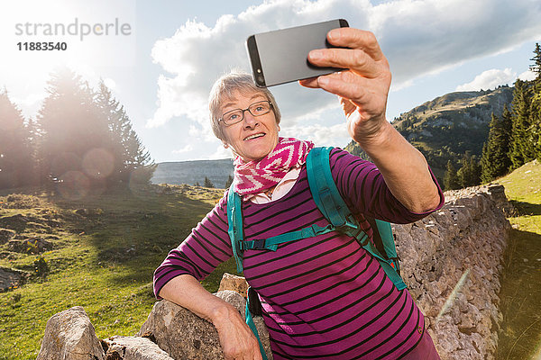 Ältere Frau  in ländlicher Umgebung an die Wand gelehnt  Selfie  mit Smartphone  Genf  Schweiz  Europa