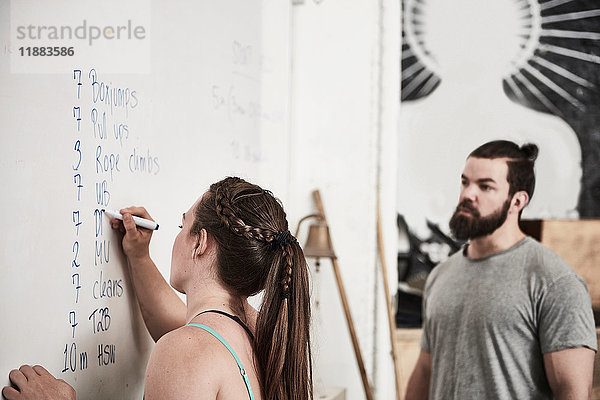 Fitnesstrainer schreibt in einer Cross-Trainingshalle an die Tafel