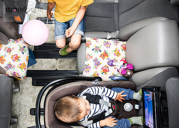 Baby und großer Bruder sehen sich im Auto einen Film an