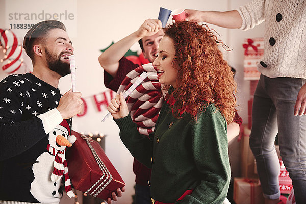 Junge Männer und Frauen singen auf der Weihnachtsfeier mit Scheinmikrofonen