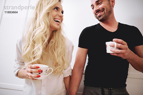 Paar zu Hause mit Kaffee  Hände haltend  Gesicht an Gesicht lächelnd