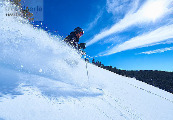 Mann fährt auf Skiern einen tief verschneiten Berghang hinunter  Aspen  Colorado  USA