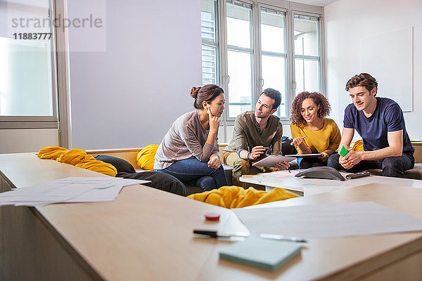 Digital-Designer auf Büro-Sofa mit Blick auf digitales Tablet