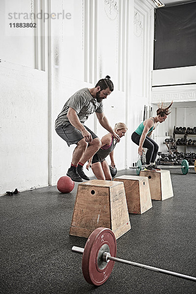 Freunde springen im Crosstraining auf die Fitness-Box