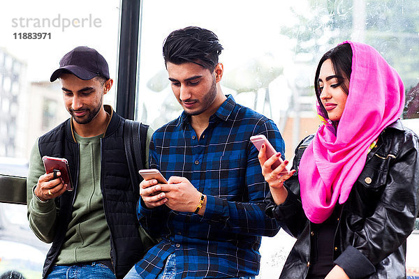 Freunde in einer Reihe  die alle auf Smartphones schauen