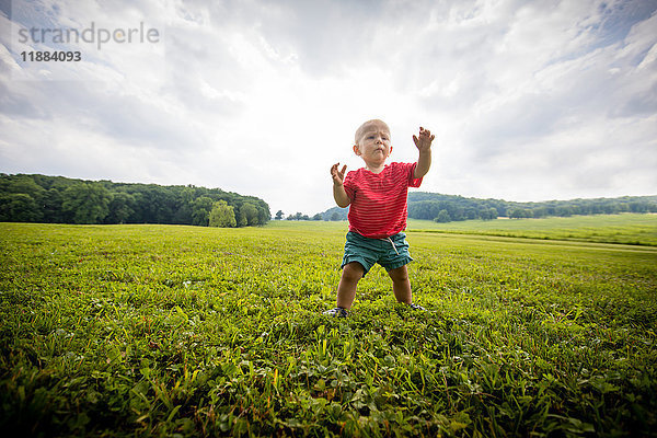 Kleiner Junge watschelt auf grasbewachsenem Feld