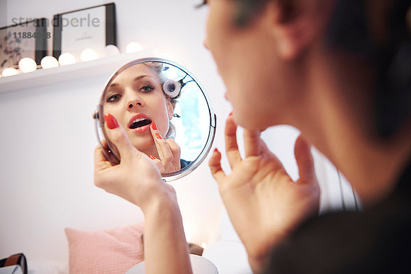 Spiegelbild einer Frau  die Lippenstift aufträgt