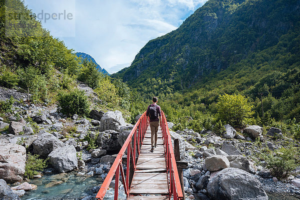 Rückansicht eines Mannes  der eine Brücke überquert  Verfluchte Berge  Theth  Shkoder  Albanien  Europa