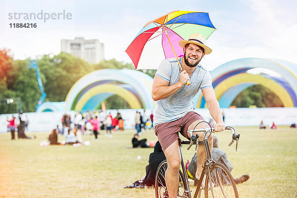 Mann mit Regenschirm fährt Fahrrad beim Festival