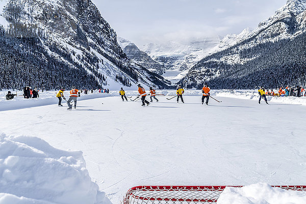 Zwei Hockeyteams treten beim Fairmont Chateau Lake Louise Teichhockeyturnier im Winter auf dem Lake Louise an; Lake Louise  Alberta  Kanada'.