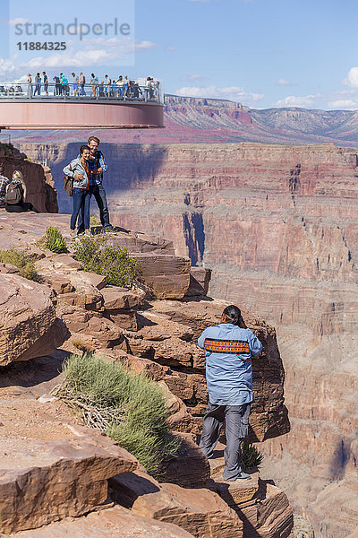 Ein amerikanischer Arbeiter fotografiert Touristen am Skywalk-Aussichtspunkt über dem Naturgebiet des West Grand Canyon in Arizona  einer beliebten Touristenattraktion  die von den amerikanischen Ureinwohnern betrieben wird; Arizona  Vereinigte Staaten von Amerika'.