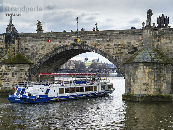 Ein Ausflugsboot fährt unter der Karlsbrücke auf der Moldau durch; Prag  Tschechische Republik'.