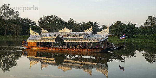 Ein Ausflugsboot schippert langsam einen ruhigen Fluss hinunter; Chiang Rai  Thailand'.