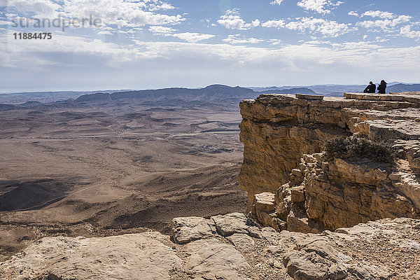 Menschen  die auf einem Felsvorsprung stehen und die Aussicht auf die zerklüftete Landschaft genießen  Ramon-Naturschutzgebiet; Mitzpe Ramon  Süddistrikt  Israel'.