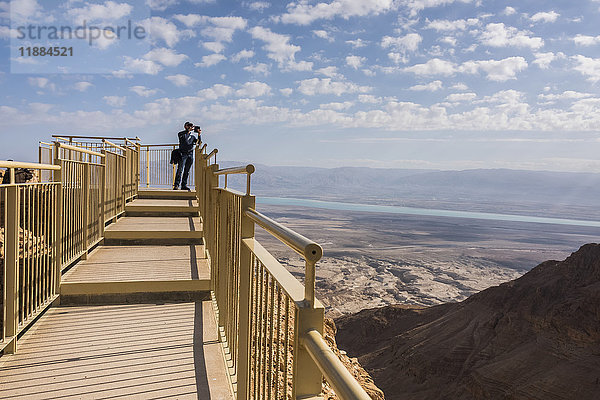 Ein Tourist steht am Ende eines Aussichtspunkts mit Blick auf die Region des Toten Meeres und die Wüste; Süddistrikt  Israel