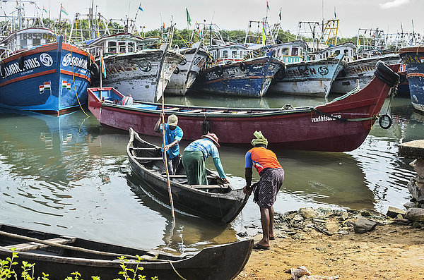 Fischer  die kleine Boote hinausschieben und bunte Fischerboote; Kadappuram  Kerala  Indien'.
