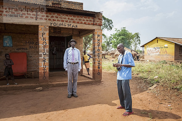 Ein Fotograf mit Kamera steht vor dem Gebäude eines Fotostudios: Uganda
