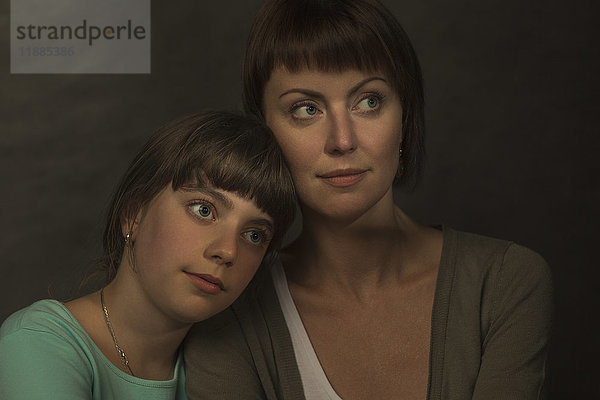 Porträt der nachdenklichen Mutter und Tochter vor grauem Hintergrund