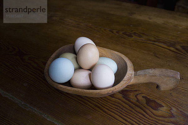 Hochwinkelansicht der Eier im Container auf Holztisch