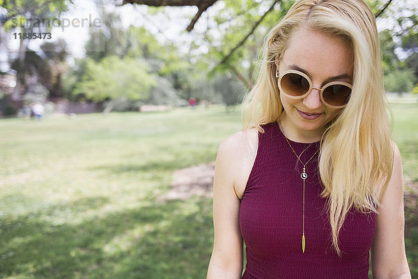 Junge blonde Frau mit Sonnenbrille im Park